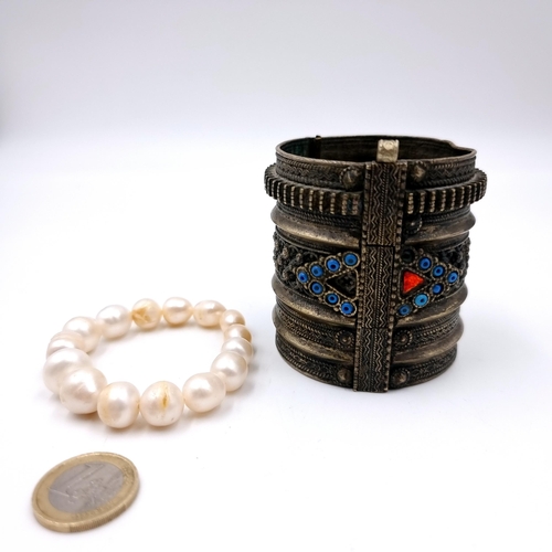 1034 - Two bracelets including a Brass Middle eastern style Tribal cuff example with locking pin and an ext... 