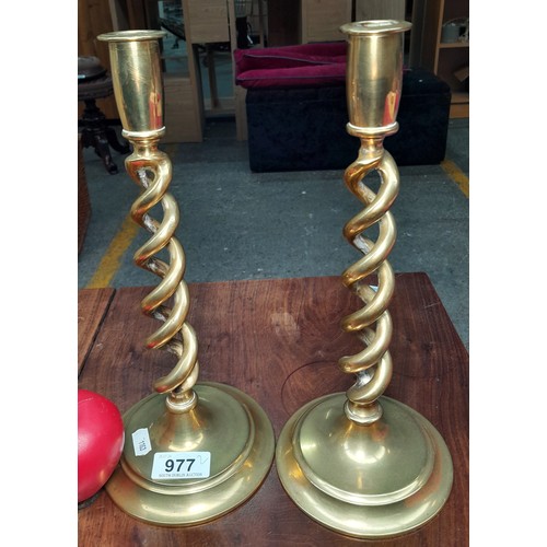 977 - A pair of heavy brass candle sticks featuring a barley twist stand.