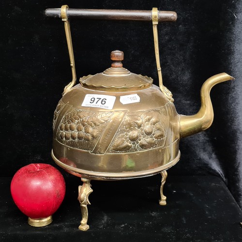 976 - A gorgeous antique brass teapot held on a trivet stand. Boasts decorative floral motifs in high reli... 