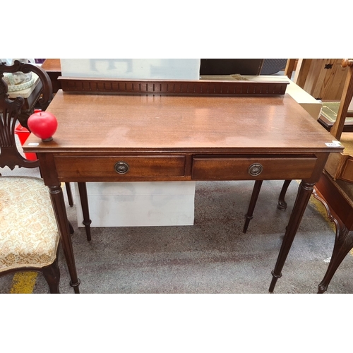 A lovely Edwardian mahogany writing desk, featuring turned legs, two drawers with brass pulls, and a decorative gallery back. From the bedroom of the lovely house In Mount Merrion the previous lot lived on top of this one. 91cm wide 75cm tall and 45cm deep