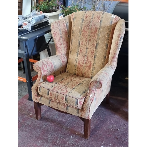 772 - A beautiful Mid Century wing back armchair fully upholstered in a demask pattern in tones of red, gr... 