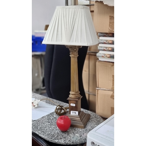 778 - A brass toned column table lamp featuring a square satin shade.