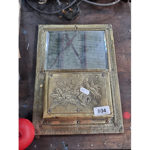 804 - A neatly sized French Art Nouveau style wall hanging brass mirror with pocket shelf.