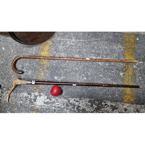 969 - Two antique walking sticks. One has a curved wooden handle and a silver tip while the other features... 