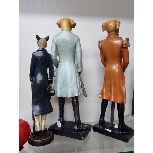 973 - Three anthropomorphic dog figurines, each dressed in elegant 18th-century attire. Crafted from resin... 