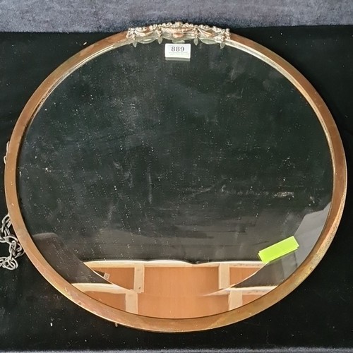 889 - An early 20th century heavy bevelled round  wall hanging mirror. Housed in a brass copper toned fram... 