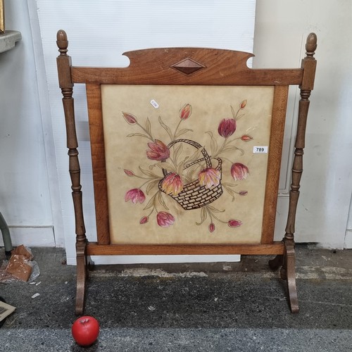 789 - A  vintage wooden fire guard with turned wood accents featuring a floral painting  behind glass scre... 