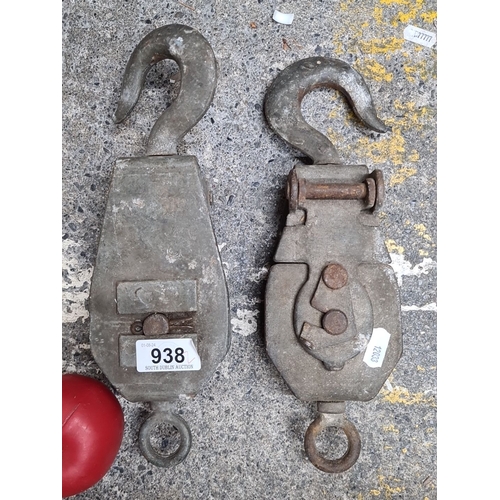 938 - A pair of vintage iron pulleys with hooks and swivel eye. The left pulley is marked 