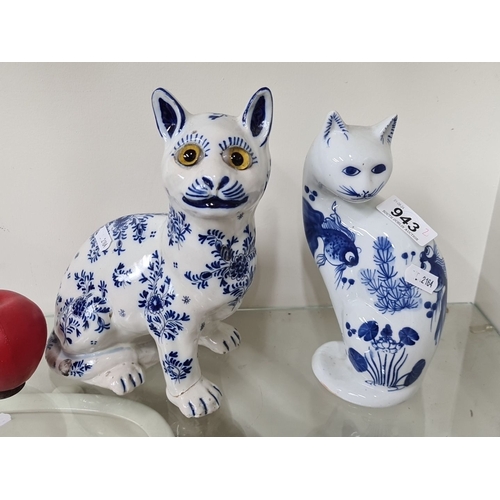 943 - Two blue-and-white ceramic cat figurines, hand-painted with intricate floral and fish designs. Each ... 