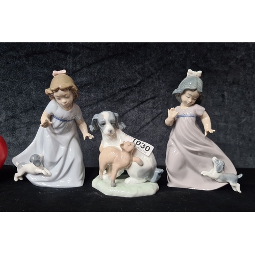 1030 - A set of three Nao by Lladro porcelain figurines. Hand-made in Spain, they depict two girls with dog... 