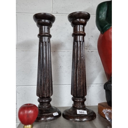 985 - A pair of tall wooden candlesticks featuring fluted design. With 'made in India' sticker to base.