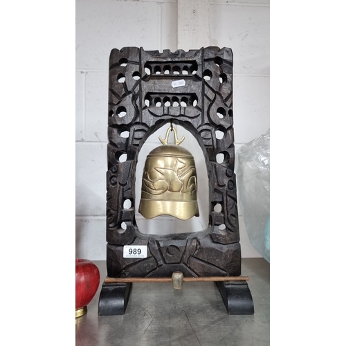 989 - An intricately carved wooden frame with a brass bell featuring carved bird motifs.