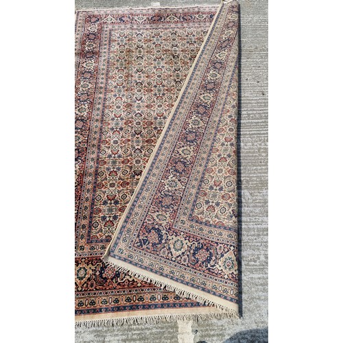 842 - Star Lot : A wonderful large Persian style wool rug in rich tones of dark blue, cream, red and dark ... 