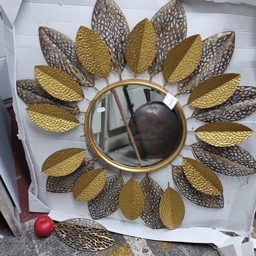 980 - A large circular mirror housed in an intricate brass toned frame surrounded by large petals. SD to t... 