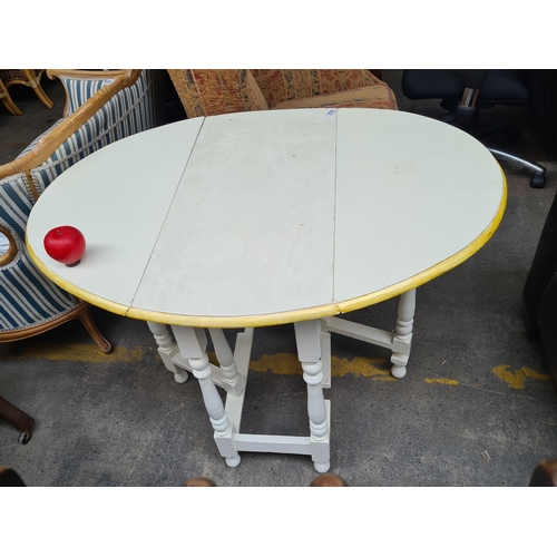 874 - A vintage painted drop-leaf table with turned legs, featuring a cream finish and golden accents on t... 