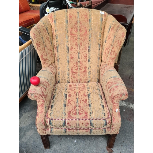 876 - A beautiful Mid Century wing back armchair fully upholstered in a demask pattern in tones of red, gr... 