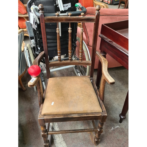 877 - An early 20th Century oak armchair featuring turned spindles and a leather upholstered seat.