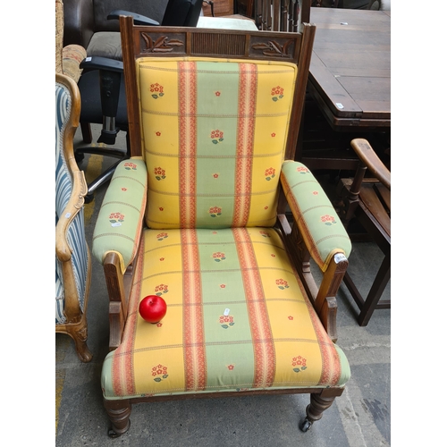 884 - Victorian-style wooden armchair with intricate carvings and floral upholstery. Features brass caster... 