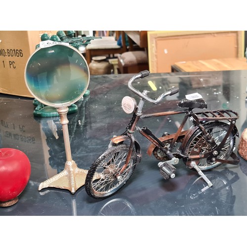 952 - Two items including a model of a push bike and a magnifying glass on a stand in the form of a birds ... 