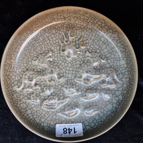 148 - An antique Chinese crackle glaze ceramic dish with two dragon like motifs in relief. Footrim shows w... 