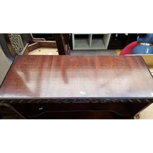 443 - A mahogany bookshelf featuring two shaped shelves and braided edging.