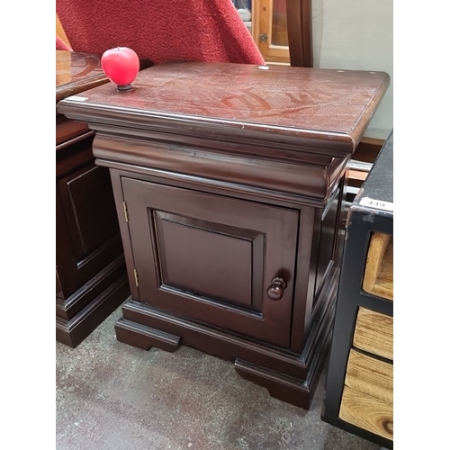 448 - A Mahogany bedside cabinet with paneled door. It features a bevelled top and stepped base. Hidden dr... 