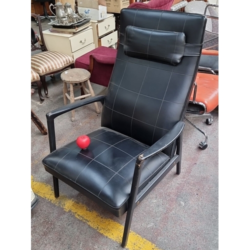 453 - Star Lot : A handsome iconic 1970's black vinyl leather armchair with chequerboard padded seat and b... 