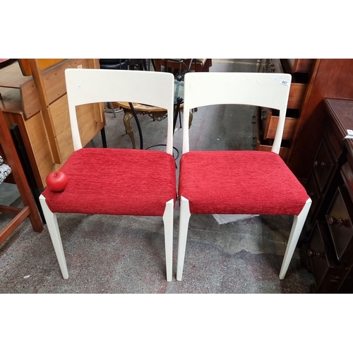 457 - A pair of mid-century modern chairs. They feature white painted wooden frames and red upholstered se... 