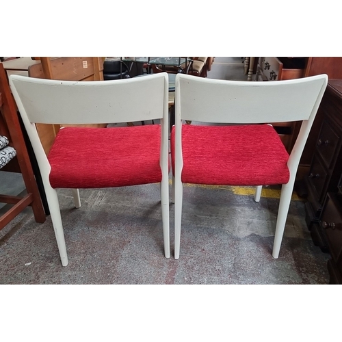 457 - A pair of mid-century modern chairs. They feature white painted wooden frames and red upholstered se... 