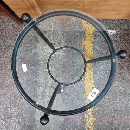 458 - Circular glass-top side table / plant stand with a heavy black wrought iron metal base.