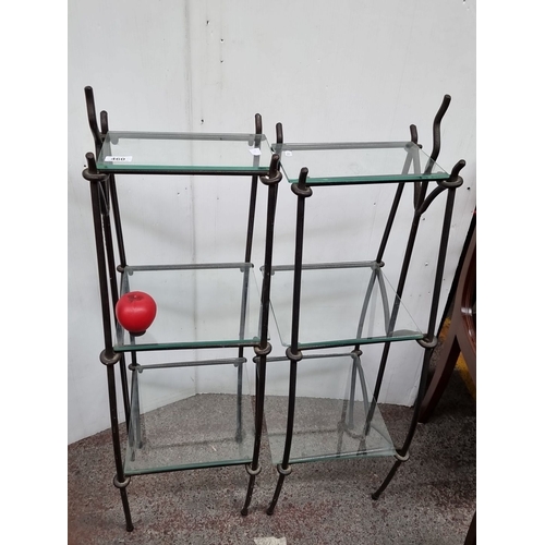 460 - Two wrought iron shelving units with five tiers of glass shelves. The design has an industrial influ... 