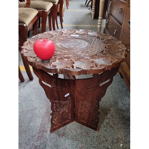 474 - An elaborately Hand-carved Indian wooden folding table with intricate floral leaf designs and a cent... 