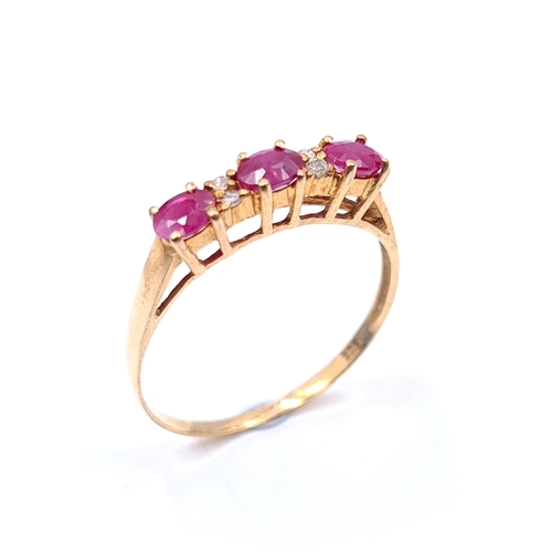 26 - Star Lot : A beautiful 10 carat gold marked to band three stone ruby ring with diamond accent mounts... 