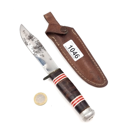 1046 - A stainless steel bowie knife with original leather sheath. Full length of knife 23cm