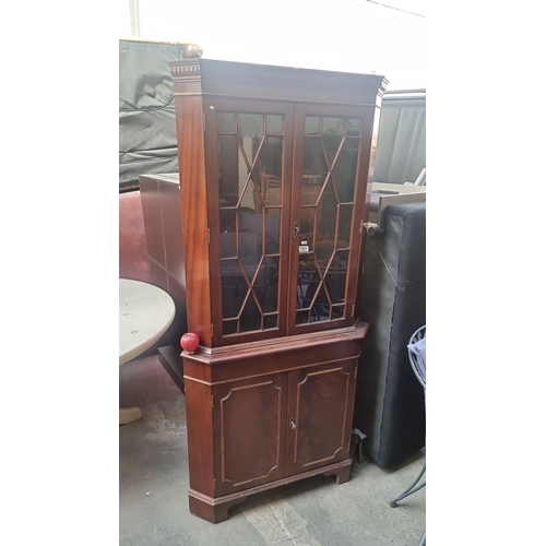 1031 - Mahogany corner cabinet equipped with glazed upper doors and a lower storage compartment. The cabine... 