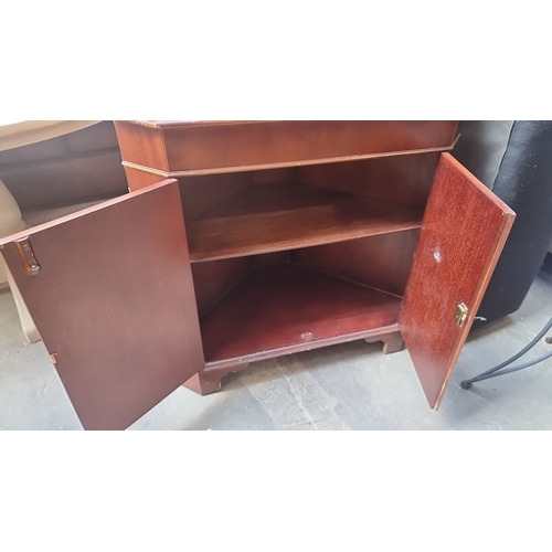 1031 - Mahogany corner cabinet equipped with glazed upper doors and a lower storage compartment. The cabine... 