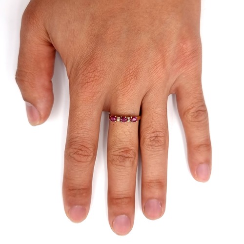 26 - Star Lot : A beautiful 10 carat gold marked to band three stone ruby ring with diamond accent mounts... 