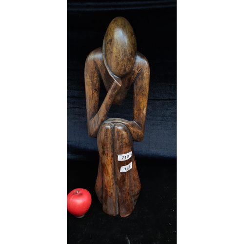 A large hardwood tribal wooden sculpture of a thinking man.