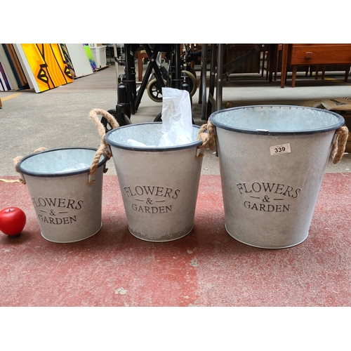 339 - Three galvanized steel buckets graduating in size with all featuring rope handles to each size. Idea... 