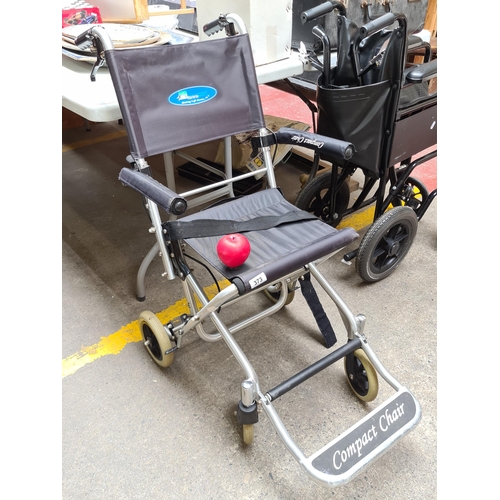 373 - A compact medical travel wheel chair with aluminium frame and foot rest.