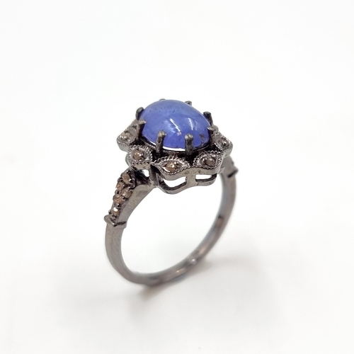 27 - Star Lot : A blue cabochon Tanzanite gemstone ring set with a diamond cluster surround and mount. Ri... 