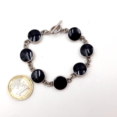 46 - A seven panel onyx stone bracelet mounted in sterling silver with T-bar clasp. Weight - 23.38 grams.