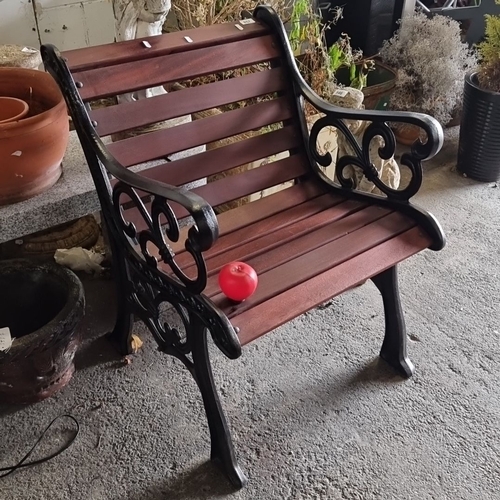 Victorian-style outdoor bench with ornate black wrought iron armrests and legs. The bench has wooden slats painted in a rich mahogany finish.