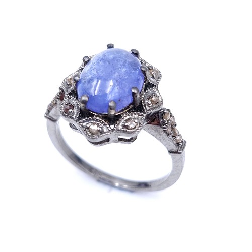 27 - Star Lot : A blue cabochon Tanzanite gemstone ring set with a diamond cluster surround and mount. Ri... 