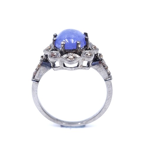 27 - Star Lot : A blue cabochon Tanzanite gemstone ring set with a diamond cluster surround and mount. Ri... 