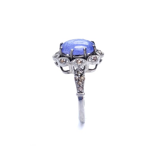 27 - Star Lot : A blue cabochon Tanzanite gemstone ring set with a diamond cluster surround and mount. Ri... 