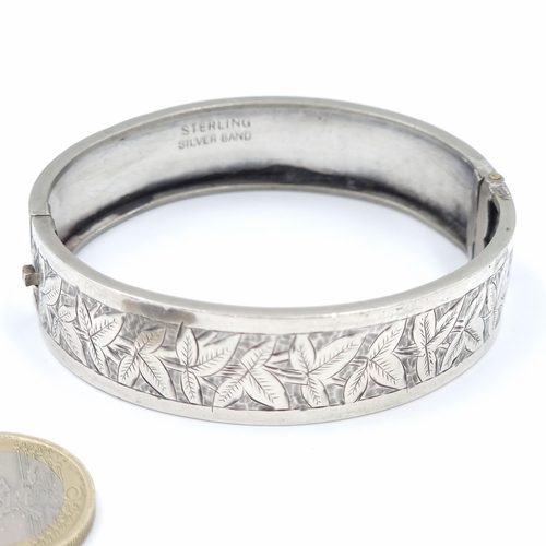 32 - A thick silver bangle with foliette detailing marked silver. Weight - 17 grams.