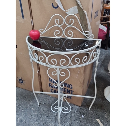 972 - White wrought iron console table features intricate scrollwork and a black glass top.