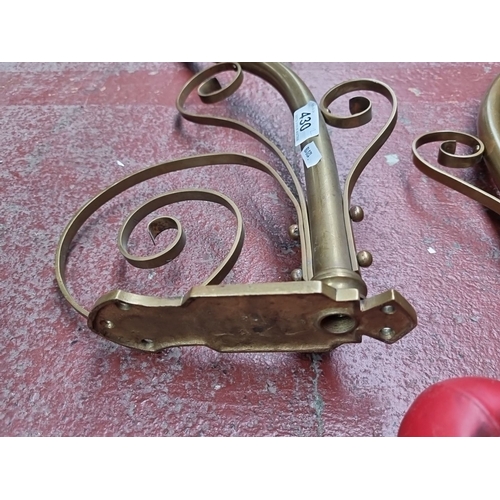 430 - Pair of brass wall-mounted candle sconces with ornamental scrollwork design.