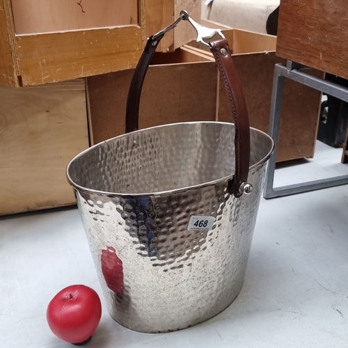 468 - Hammered metal Champagne bucket with leather handle, featuring decorative metal detailing. Measures ... 